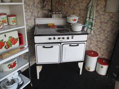 an old fashioned stove with pots and pans on it's shelves in a kitchen