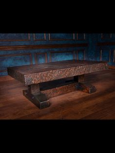 a wooden table sitting on top of a hard wood floor next to a blue wall