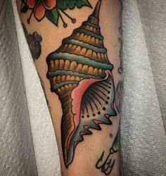 a close up of a person's leg with tattoos on it and an image of a shell