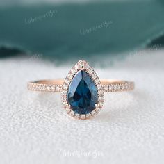 an engagement ring with a pear shaped blue sapphire surrounded by diamonds