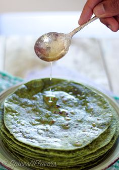 a stack of pancakes on a plate being drizzled with green tea syrup