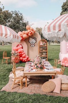 an outdoor party with pink and white balloons on the ground, tables and chairs are set up