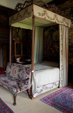 a four poster bed sitting in a bedroom next to a rug on the floor and walls