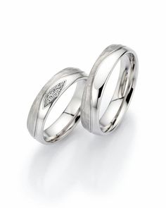 two white gold wedding rings with diamonds on each side and an arrow in the middle