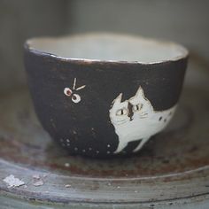 a black and white bowl with a cat design on the side, sitting on a table