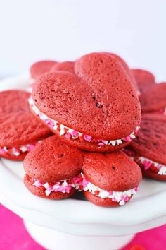 red velvet cookies with white and pink sprinkles are stacked on a cake plate