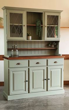 an old fashioned china cabinet with glass doors and cupboards on the top, sitting in a room