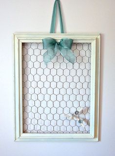 a white frame with a green bow hanging from it's side on a wall