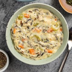 a bowl filled with soup next to bowls of seasoning and spoons on a table