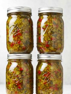 four jars filled with pickled vegetables sitting on top of a white countertop next to each other