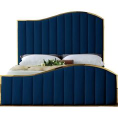 an upholstered bed with blue velvet headboard and white linens on it