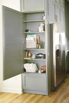 a kitchen with gray cupboards and stainless steel refrigerator freezer next to wooden flooring