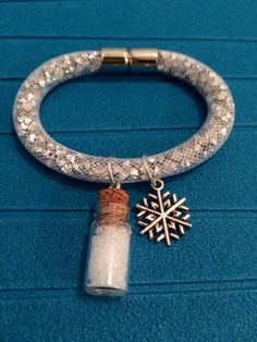 a silver bracelet with a snowflake charm and a corked bottle on it