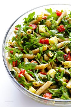 a glass bowl filled with pasta salad on top of a table