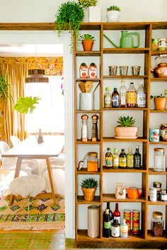 a room with shelves filled with bottles, plants and other things on the wall next to a table