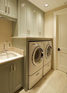 a washer and dryer in a small room with light colored cabinets on the walls