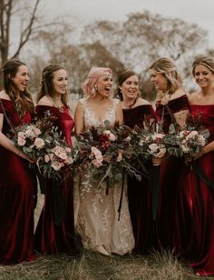 a group of women standing next to each other wearing red dresses and holding bouquets