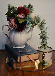 a tea pot with flowers on top of a table