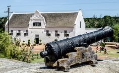 an old cannon sitting on top of a stone wall in front of a white building