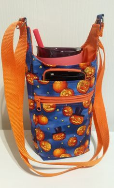 a cell phone in a blue bag with pumpkins on it and an orange strap