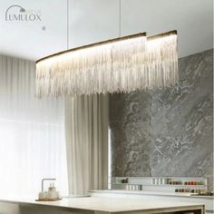 an elegant chandelier hangs from the ceiling above a dining table in a modern kitchen