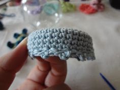 a crocheted object is being held up by someone's hand on a table