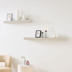 two white shelves on the wall with vases and other items sitting on top of them