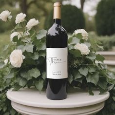 a bottle of wine sitting on top of a table next to white flowers and greenery