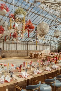 a long table is set with place settings for an event in a glass walled building