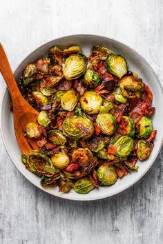 brussel sprouts in a white bowl with a wooden spoon on the side