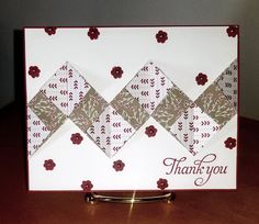 a thank you card with red flowers and white squares on it, sitting on a table