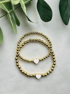 Sweet and adorablematching mother daughter bracelet set. These 18k gold filled bracelets are centered with a white enamel and gold heart. Perfect gift for a new mom and daughter or for mom to gift her little on. Bracelets are beaded on high quality stretch cord and secured.  - 4mm 18k gold filled beads    5mm 18k gold filled beads   8mm enamel heart bead  - If you need more then 1 mini, please send me a message for a custom listing  - Each purchase is sent in a velvet drawstring bag making the p White Heart Charm Bracelet For Anniversary, Gold Hypoallergenic Charm Bracelet For Friendship, Gold Heart-shaped Stackable Jewelry, Hypoallergenic Gold Charm Bracelet For Friendship, Gold Charm Bracelet With Heart Beads For Valentine's Day, Personalized Gold Beaded Bracelets For Valentine's Day, Gold Heart Beads Bracelet For Valentine's Day, Gold Bracelet With Heart Charm For Mother's Day, Gold Heart Bracelet Nickel Free