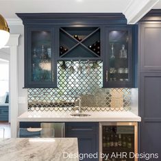 a kitchen with blue cabinets and marble counter tops, wine rack on the wall above the sink