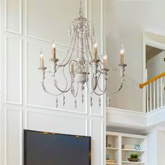 a chandelier hanging from the side of a white wall next to a flat screen tv