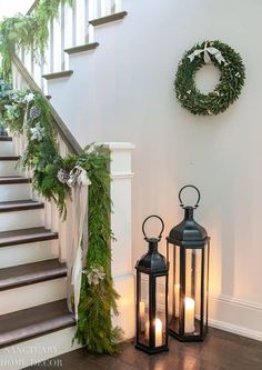 two lanterns sitting next to each other on the ground in front of stairs with wreaths