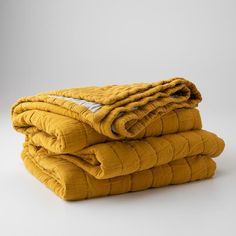 three yellow blankets stacked on top of each other in front of a white background,