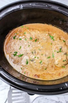 a crock pot filled with meat and gravy