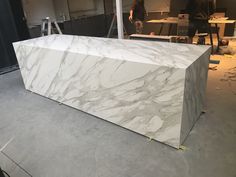 a large white marble counter top in a room with workers working on the wall behind it