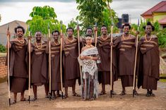 a group of people standing next to each other in front of trees and bushes with sticks