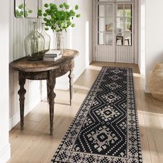 a room with a rug, table and mirror on the wall next to it in front of a door