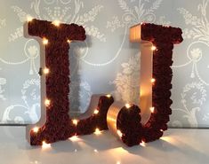 the word love is made out of red roses and lit up with fairy lights on it