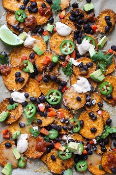 a tray filled with potato wedges topped with black beans, avocado and sour cream