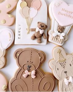 cookies decorated with teddy bears and balloons on a white table top, including one for a baby's first birthday