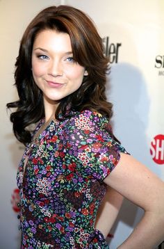 a beautiful young woman standing in front of a red carpet with her hands on her hips