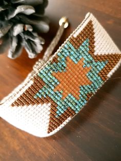 a beaded bracelet sitting on top of a wooden table next to a pine cone