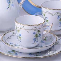 a white tea set with blue flowers and gold trimmings