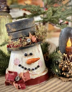 a snowman made out of wood sitting on top of a table next to candles