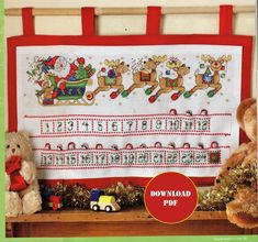 two teddy bears are sitting in front of a cross - stitched christmas banner with santa's sleigh and reindeers