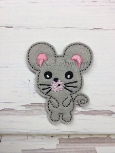 a gray mouse with pink ears is sitting on a white wooden surface and it's saying happy birthday