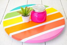 a potted plant sitting on top of a multicolored wooden table topped with a jar